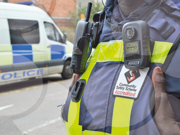 Image shows a CSAS officer in the foreground with a police van in the background
